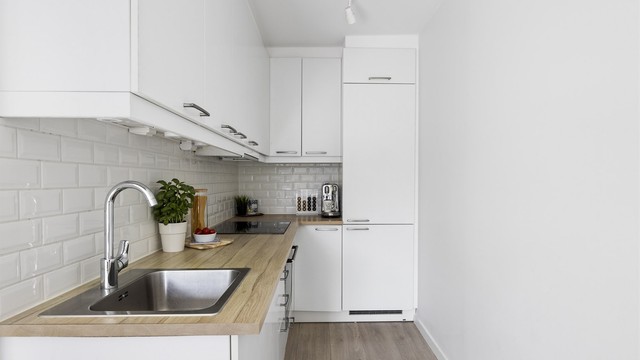 Kjøkken med åpen løsning mot stue. Pen kjøkkeninnredning med glatte fronter, benkeplate med laminert overflate og fliser mellom kjøkkenbenk og overskap