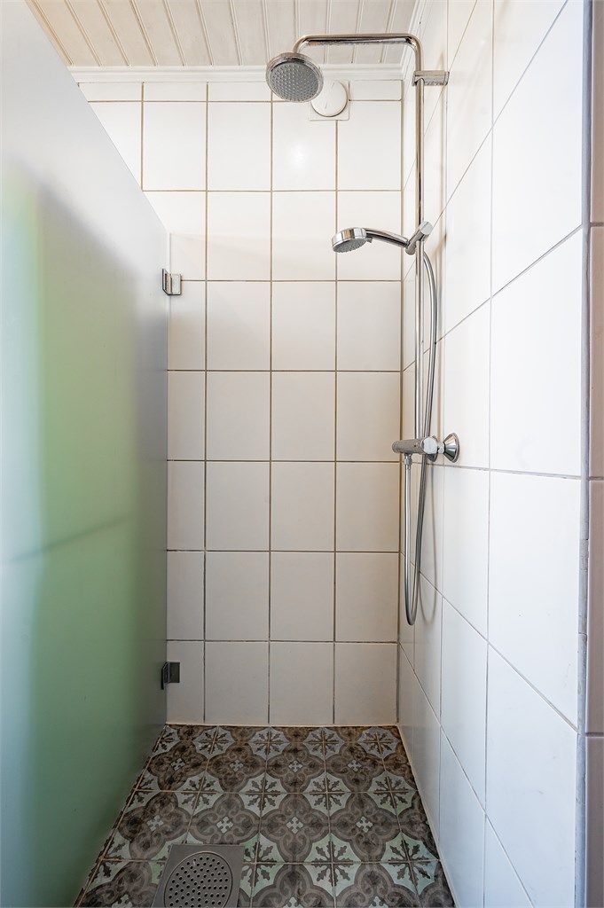 Flislagt dusjnisje med dusjvegg i glass.