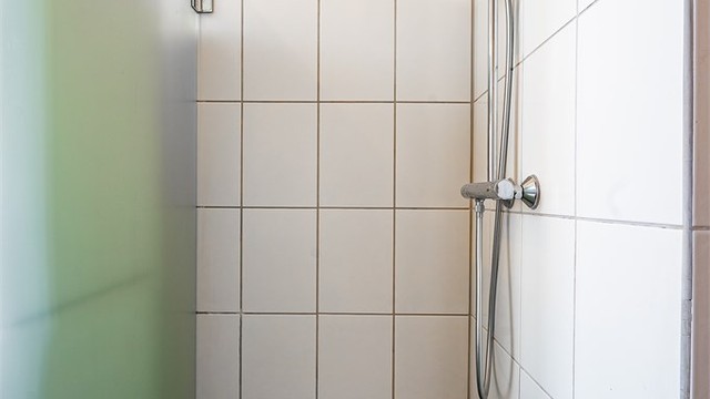 Flislagt dusjnisje med dusjvegg i glass.