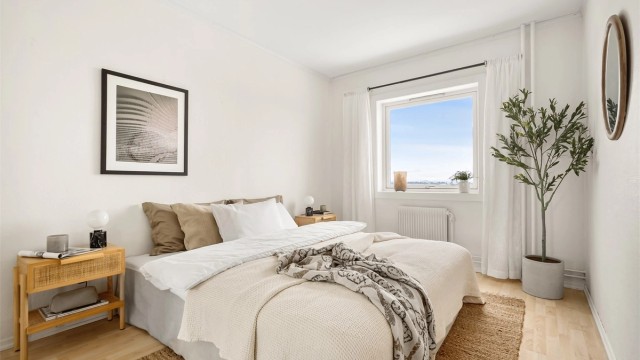 Soverommet har plass til dobbeltseng og nattbord, med laminat på gulvet.