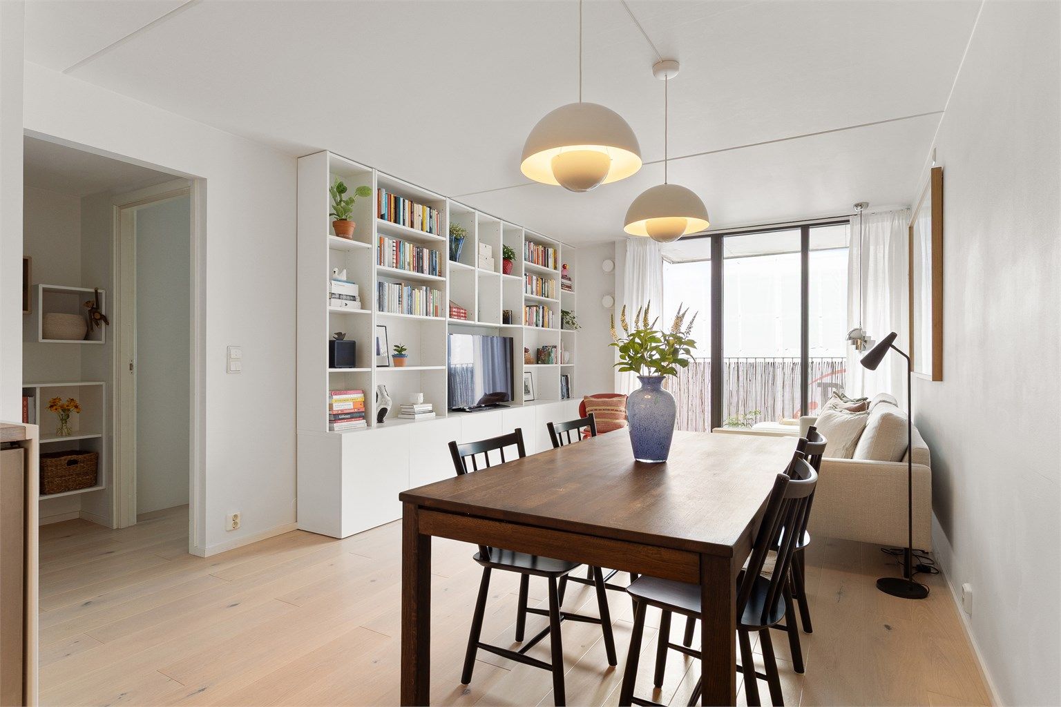 En innbydende og harmonisk stue med plass til både lange middager og late kvelder i sofaen. De gjennomgående, lyse overflatene og den elegante en-stavs parketten gir rommet et moderne og helhetlig uttrykk.