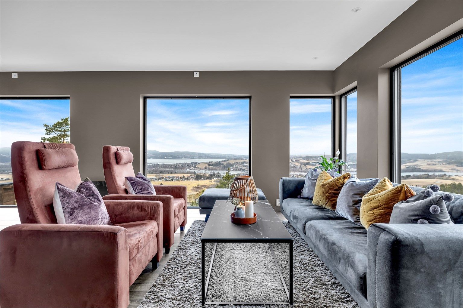 Lys og stilfull stue med store vinduer som rammer inn utsikten mot bl.a Fetsund, Glomma og Øyeren