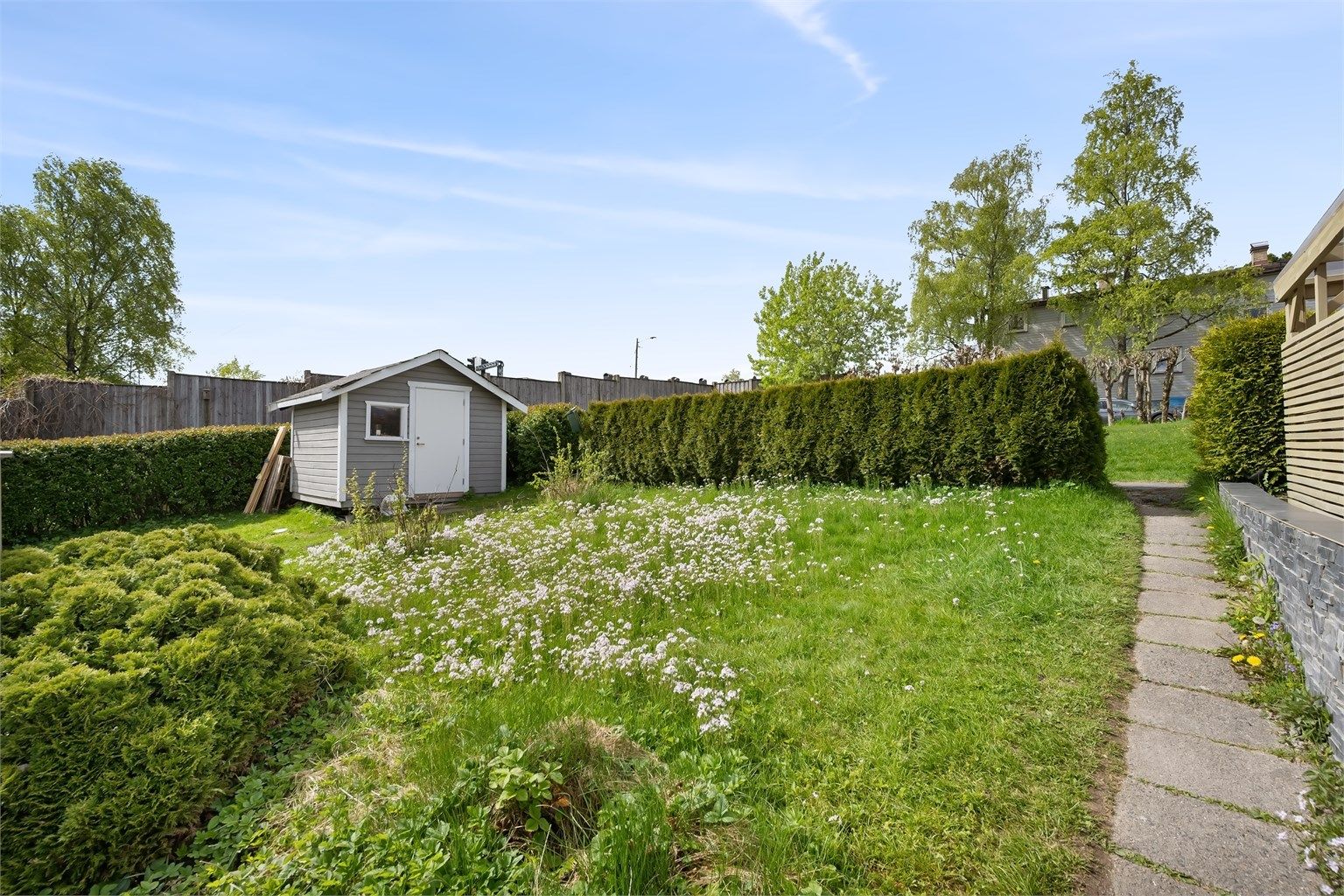 Hagen er pent opparbeidet med plen og beplantning.