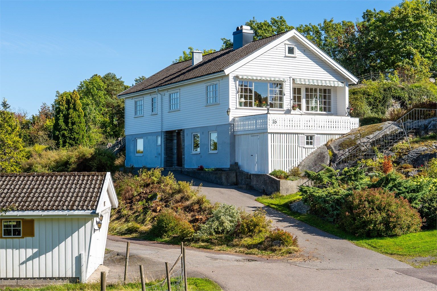 Asfaltert adkomstvei opp til boligen med frittstående garasje plassert ved innkjøringen.