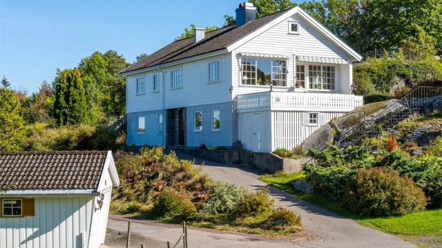 Asfaltert adkomstvei opp til boligen med frittstående garasje plassert ved innkjøringen.