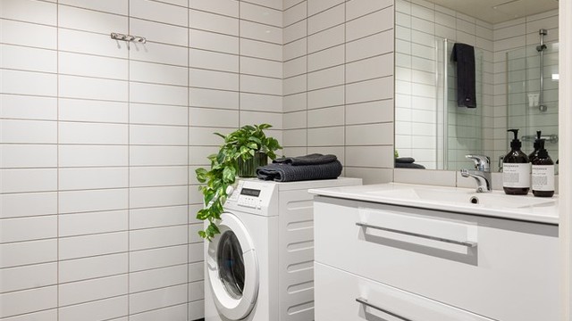 Badet har servant nedfelt i innredning, speil med belysning og opplegg for vaskemaskin.