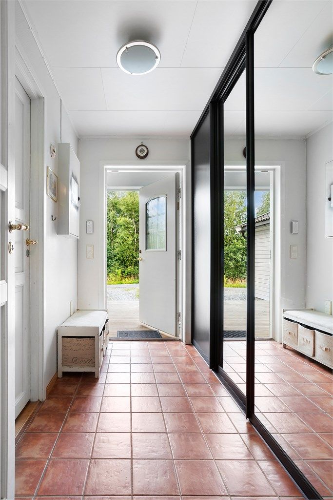 Man kommer inn i en flislagt entré med skyvedørsgarderobe