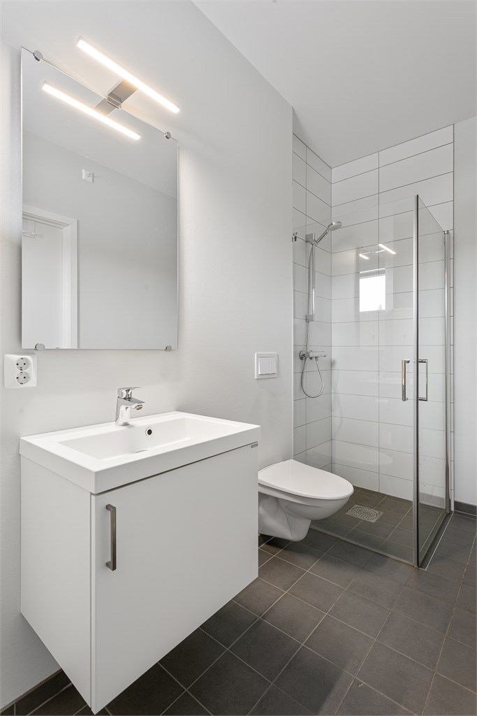 Dusjhjørne med innfellbare glassdører og vegghengt toalett for enkelt renhold.