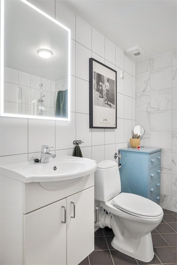 Badet er utstyrt med gulvstående toalett og heldekkende servant med skapinnredning og speil med integrert belysning samt opplegg for vaskemaskin