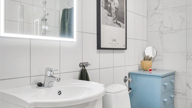 Badet er utstyrt med gulvstående toalett og heldekkende servant med skapinnredning og speil med integrert belysning samt opplegg for vaskemaskin