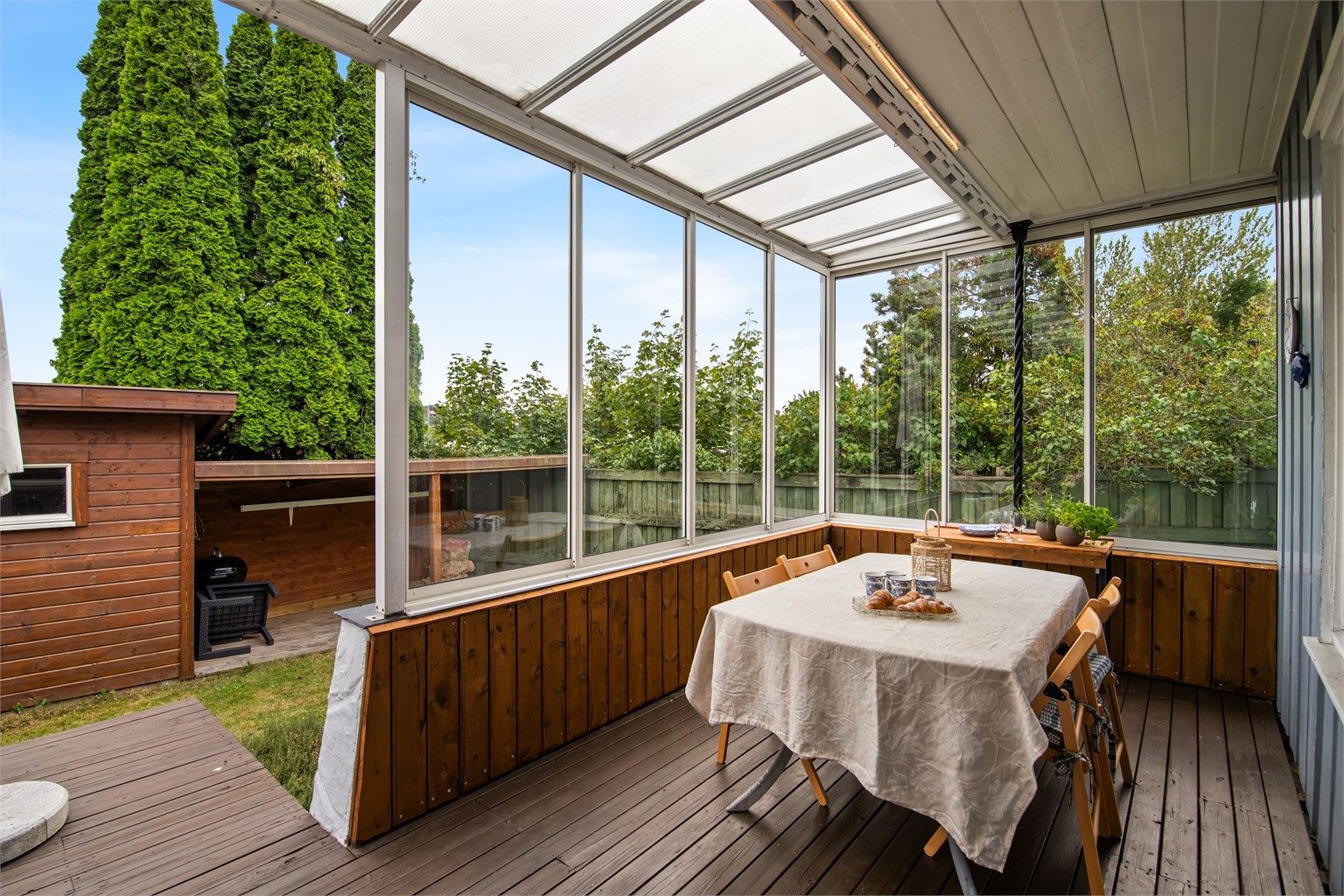  En del av uteplassen er innglasset, slik at du kan sitte lunt og skjermet – perfekt for å nyte lange sommerkvelder, uansett vær og vind.