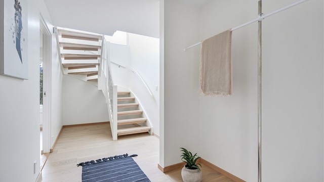 Hallen ønsker velkommen med parkett på gulvet og en malt tretrapp med eiketrinn som binder etasjene sammen.