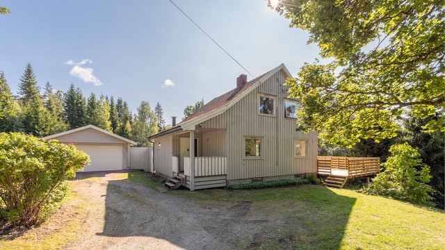 Gruset gårdsplass med biloppstillingsplass foran garasjen.