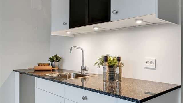 Den enkle kjøkkeninnredningen har glatte fronter og integrerte spotter.