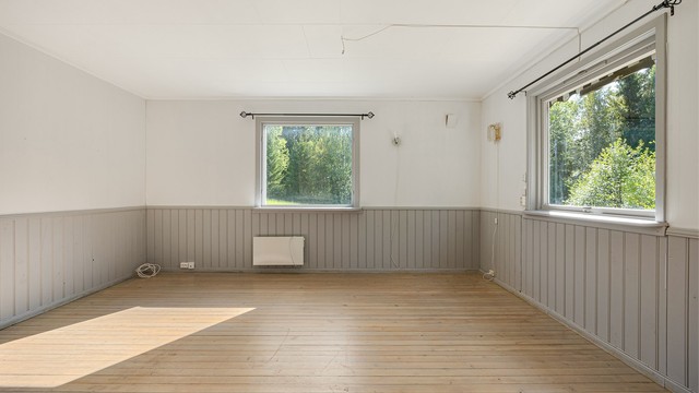 Rommet har panel på deler av veggene og vinduer som vender ut mot hagen.
