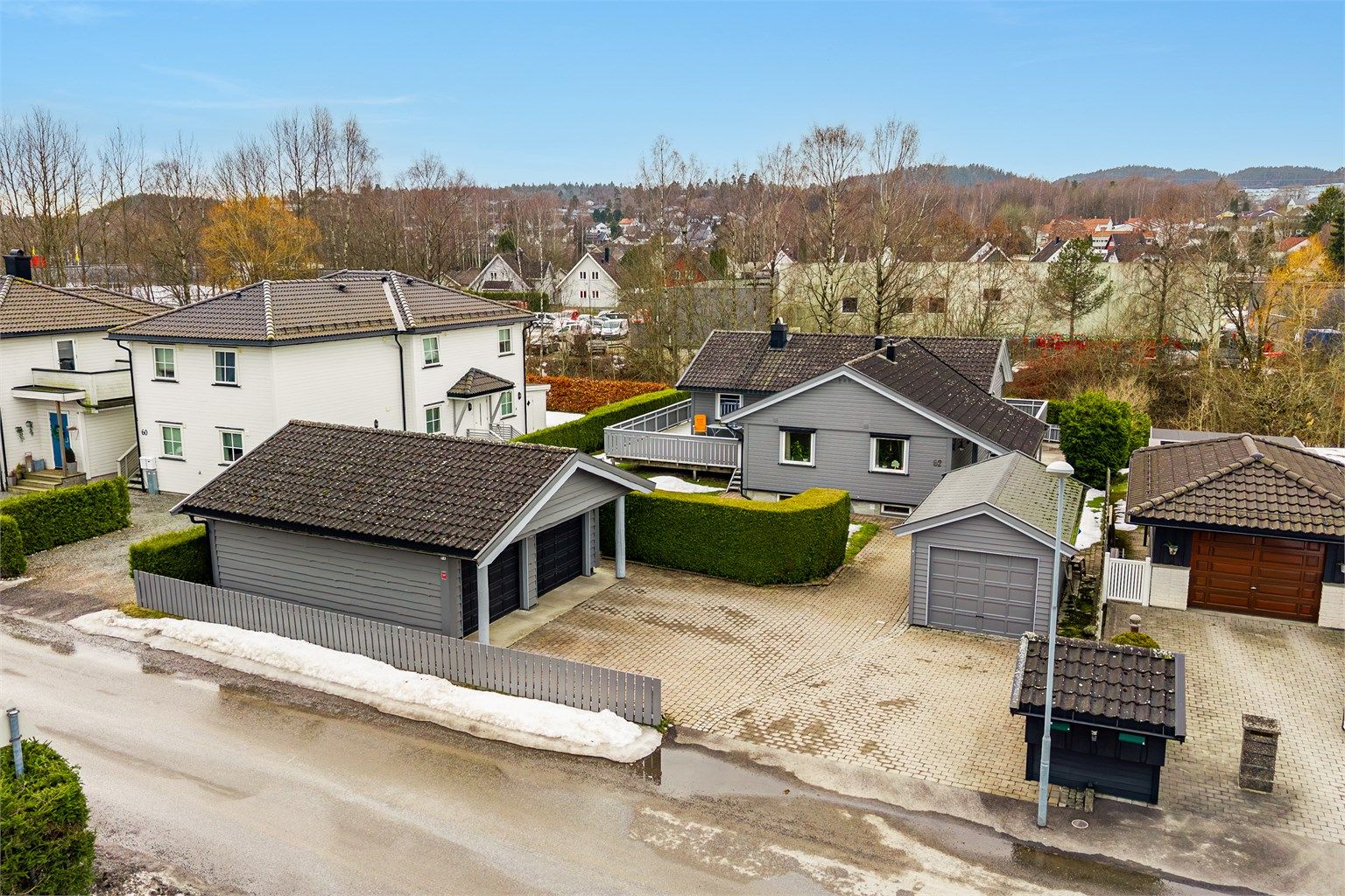 Eiendommen har stor gårdsplass med belegningsstein, dobbel garasje og en enkel garasje.