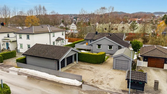 Eiendommen har stor gårdsplass med belegningsstein, dobbel garasje og en enkel garasje.