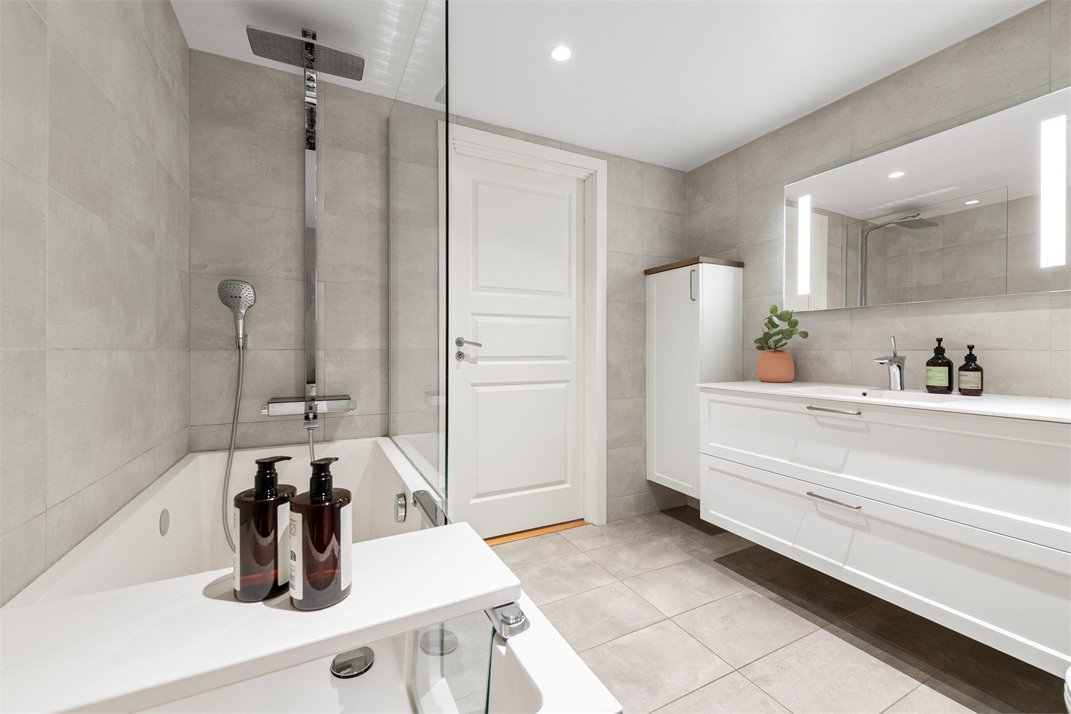 Badet er utstyrt med badekar med både regn- og hånddusj, vegghengt toalett og en bred servantinnredning