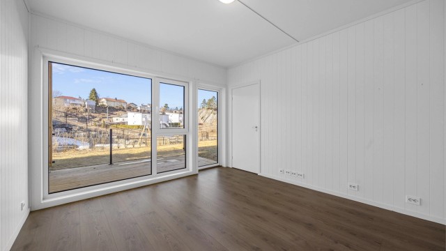 Leiligheten er en treroms med store vindusflater og god takhøyde flere rom.