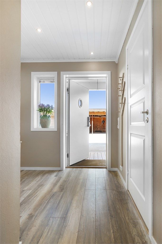 Man kommer inn i  en innbydende entré med varmekabler i gulv og downlights i tak.