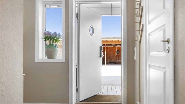 Man kommer inn i en innbydende entré med varmekabler i gulv og downlights i tak.