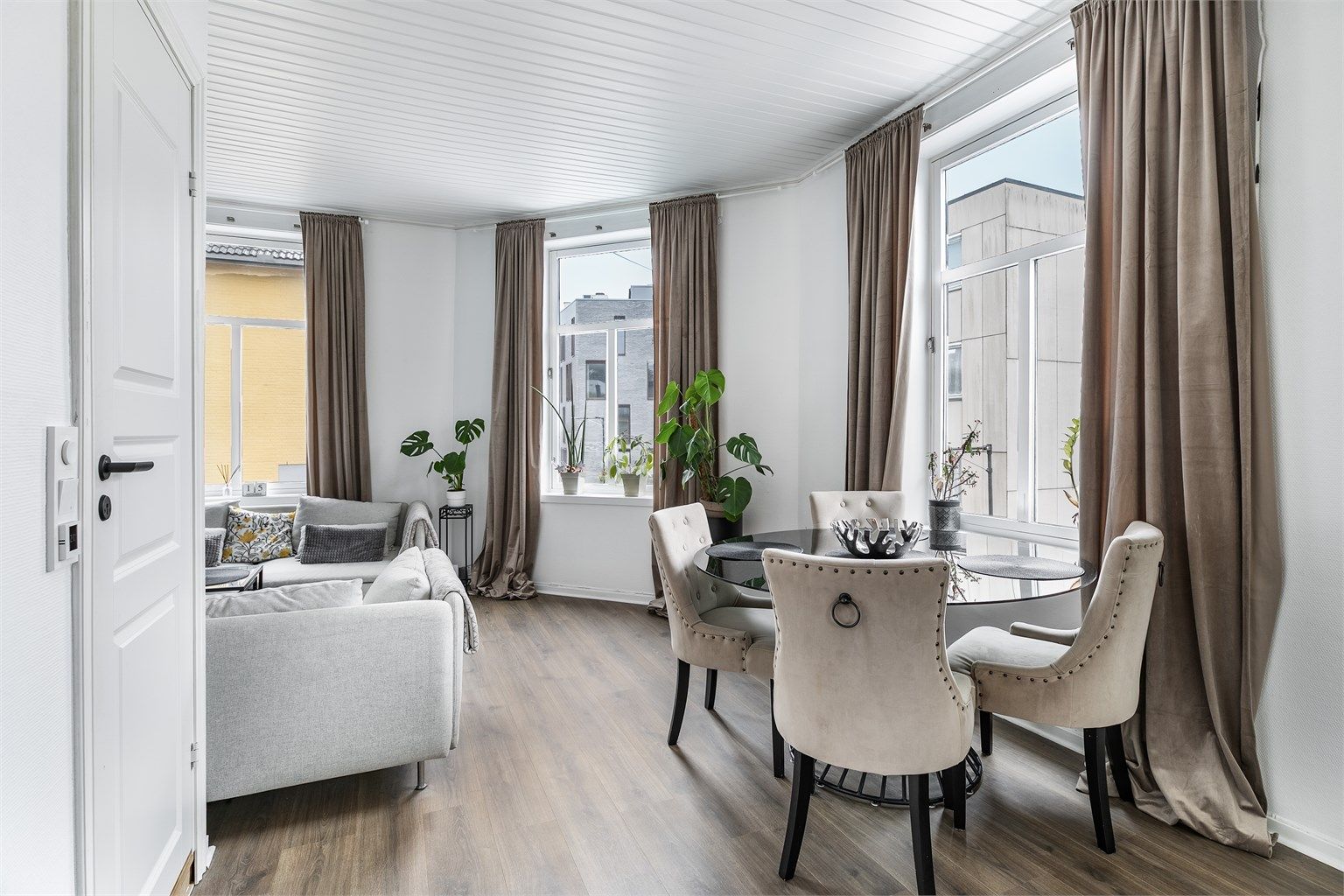 Høyreiste og atmosfærefremmende krysspostvinduer fyller stuen med naturlig lys fra tre vinkler.