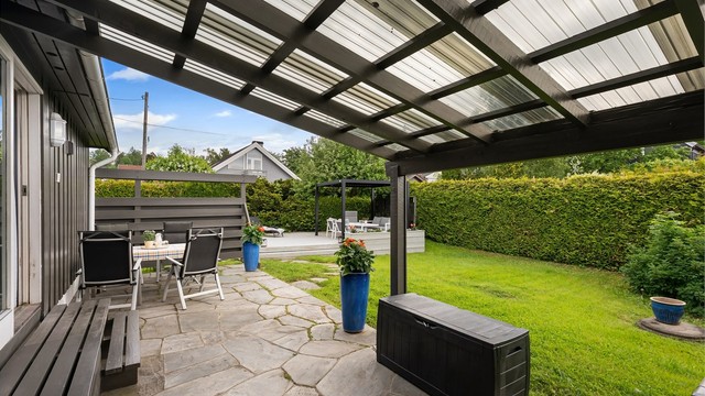 Den delvis overbygde terrassen utenfor gangen gir en lun uteplass, selv på regnfulle dager.