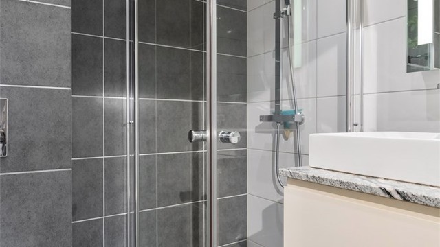 Dusjsonen har innfellbare glassdører og et dusjarmatur med både hånddusj og regndusj.