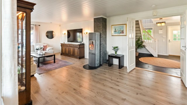 Romslig og lys stue med peisovn.