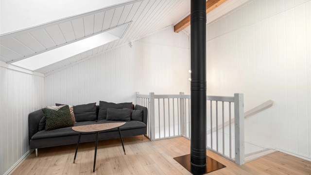 Trivelig loftstue med koselig sofakrok ved trappeåpningen - et lunt sted for avslapping, TV-titting eller lesestund