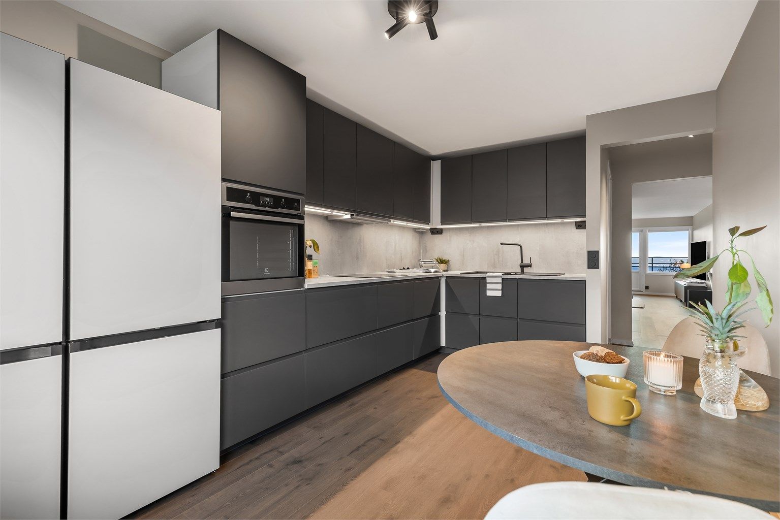 Kjøkken med innredning fra 2023. Glatte fronter. Benkeplate med laminert overflate. Kjøkkenvask med armatur. Integrert stekeovn, platetopp og oppvaskmaskin.