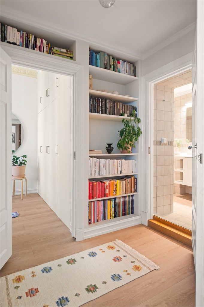 Plassbygde bokhyller gir både karakter og praktisk oppbevaring i passasjen mot bad og soverom.