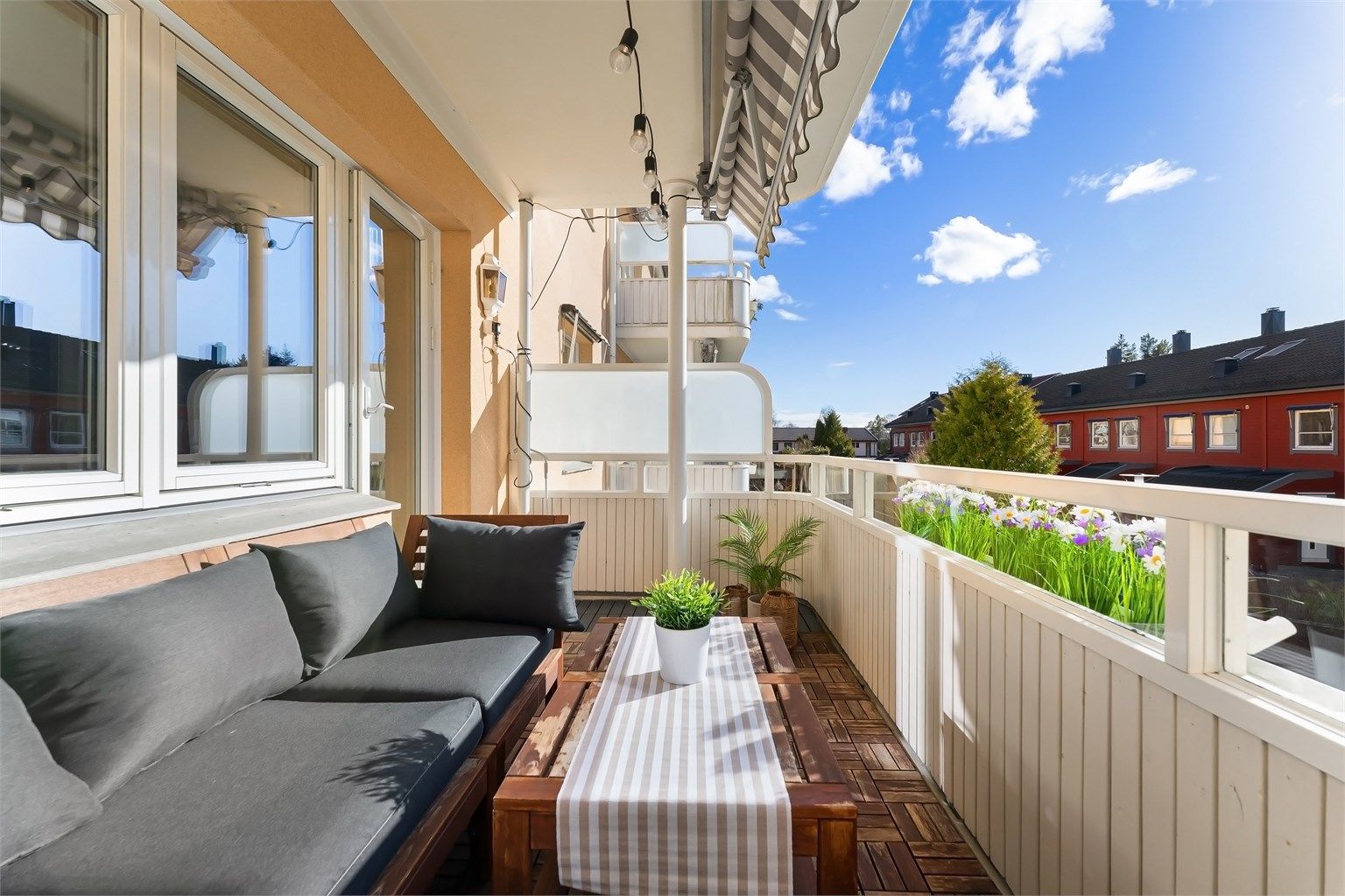 Balkongen er belagt med terrasseheller og har et rekkverk av tre.