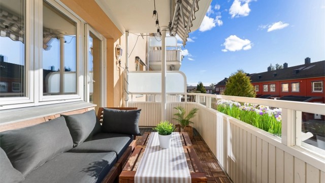 Balkongen er belagt med terrasseheller og har et rekkverk av tre.
