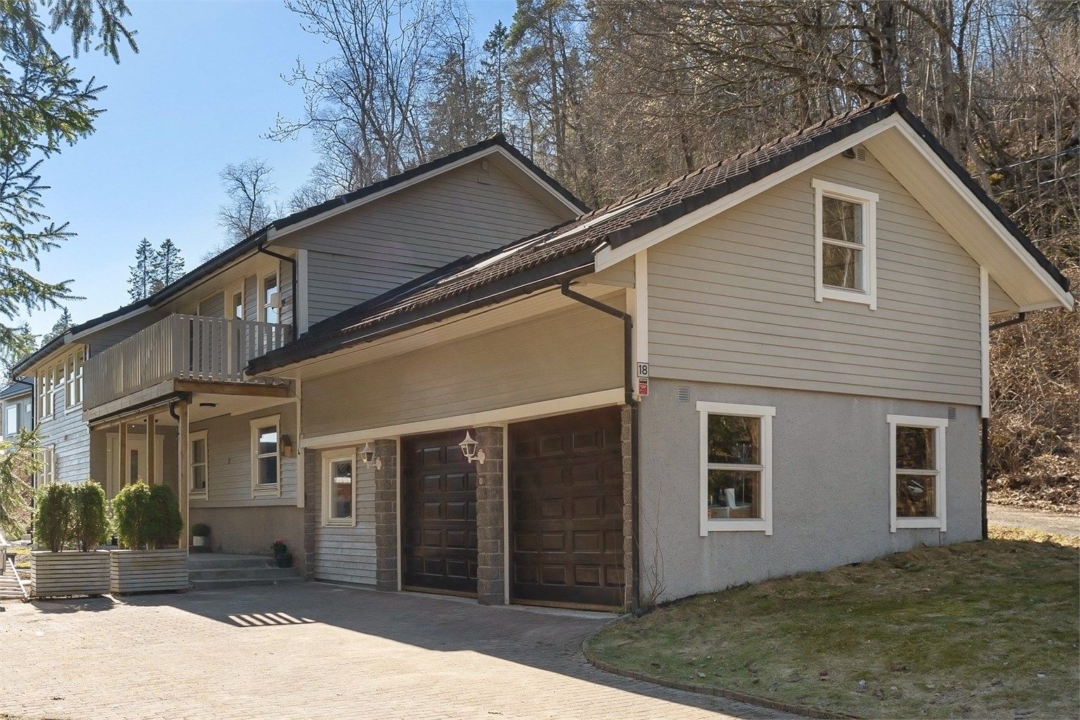 Eiendommen har en stor, steinlagt gårdsplass og en tilliggende dobbelgarasje med elektriske leddporter, som gir rikelig med parkerings- og lagringsplass.