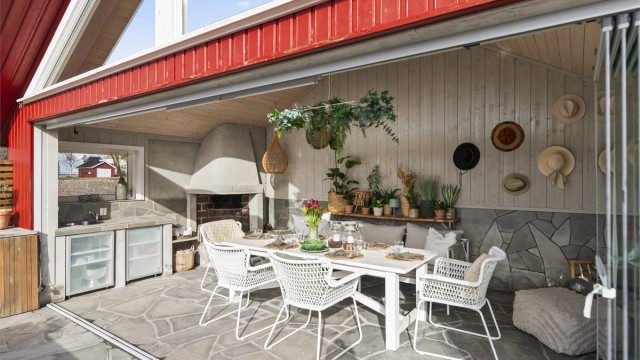 Her er det plassbygget utekjøkken og en stor, åpen peis som skaper stemning på kjølige kvelder.