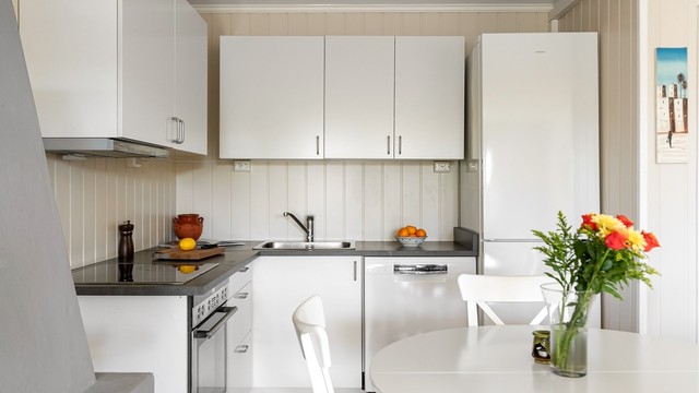 I åpen løsning mot stuen har du kjøkkenet med glatte fronter på skap og skuffer, benkeplate med laminert overflate og kjøkkenvask