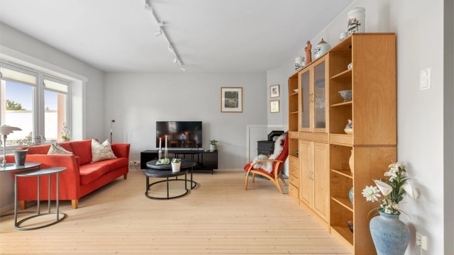 Stuen er lys og romslig med god plass til en sofagruppe, stuebord og en skjenk eller et vitrineskap.
