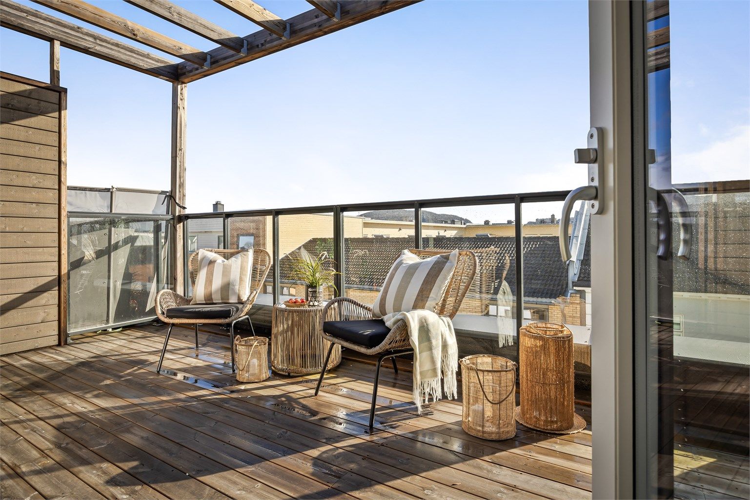 Balkong ved stue med terrassebord på gulv og glassrekkverk 