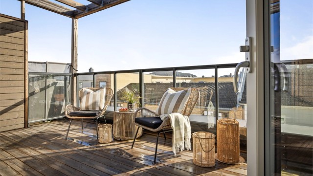Balkong ved stue med terrassebord på gulv og glassrekkverk