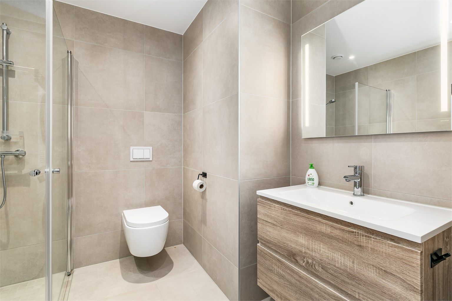 Badet har tidsaktuelle fliser av storformat på både gulv og vegger som skaper helhet. Spotter er innfelt i himlingen og kan dimmes.