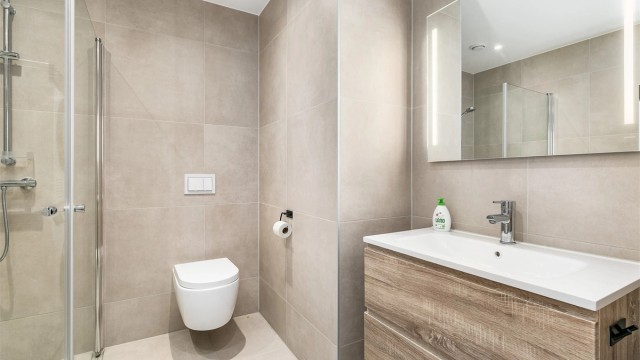 Badet har tidsaktuelle fliser av storformat på både gulv og vegger som skaper helhet. Spotter er innfelt i himlingen og kan dimmes.