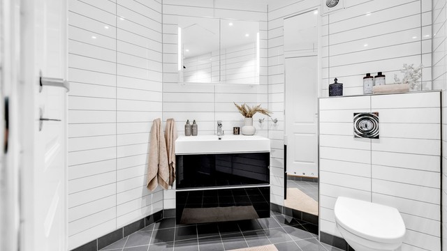 Badet er innredet med et vegghengt klosett, servant nedfelt i en skuffeseksjon og speil med integrert belysning. Det er opplegg for vaskemaskin.