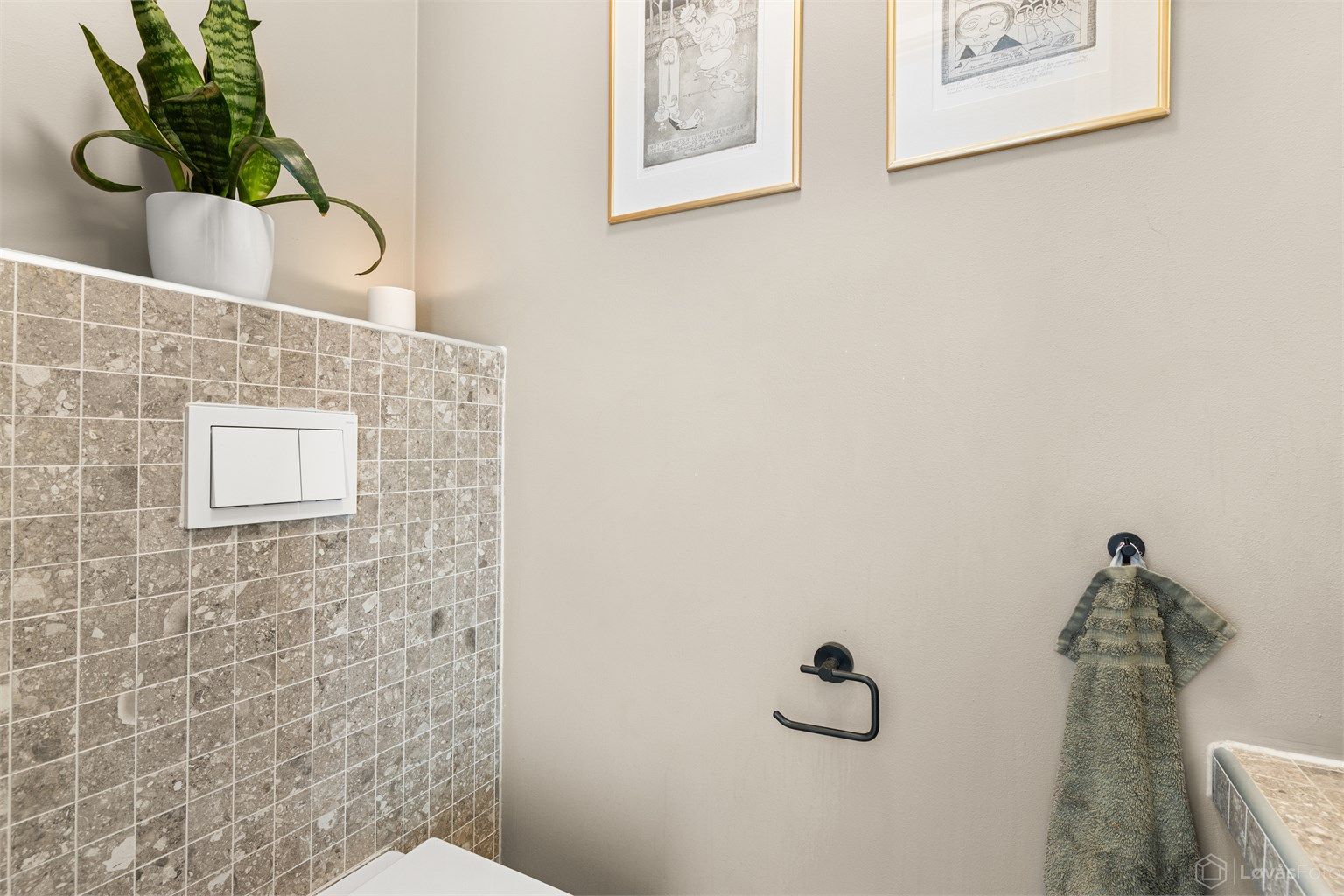 Rommet er innredet med vegghengt toalett og en flislagt benkeplate med ovenpåliggende servant.