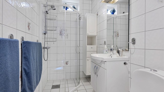 Flislagt bad med dusjløsning, servantinnredning og toalett