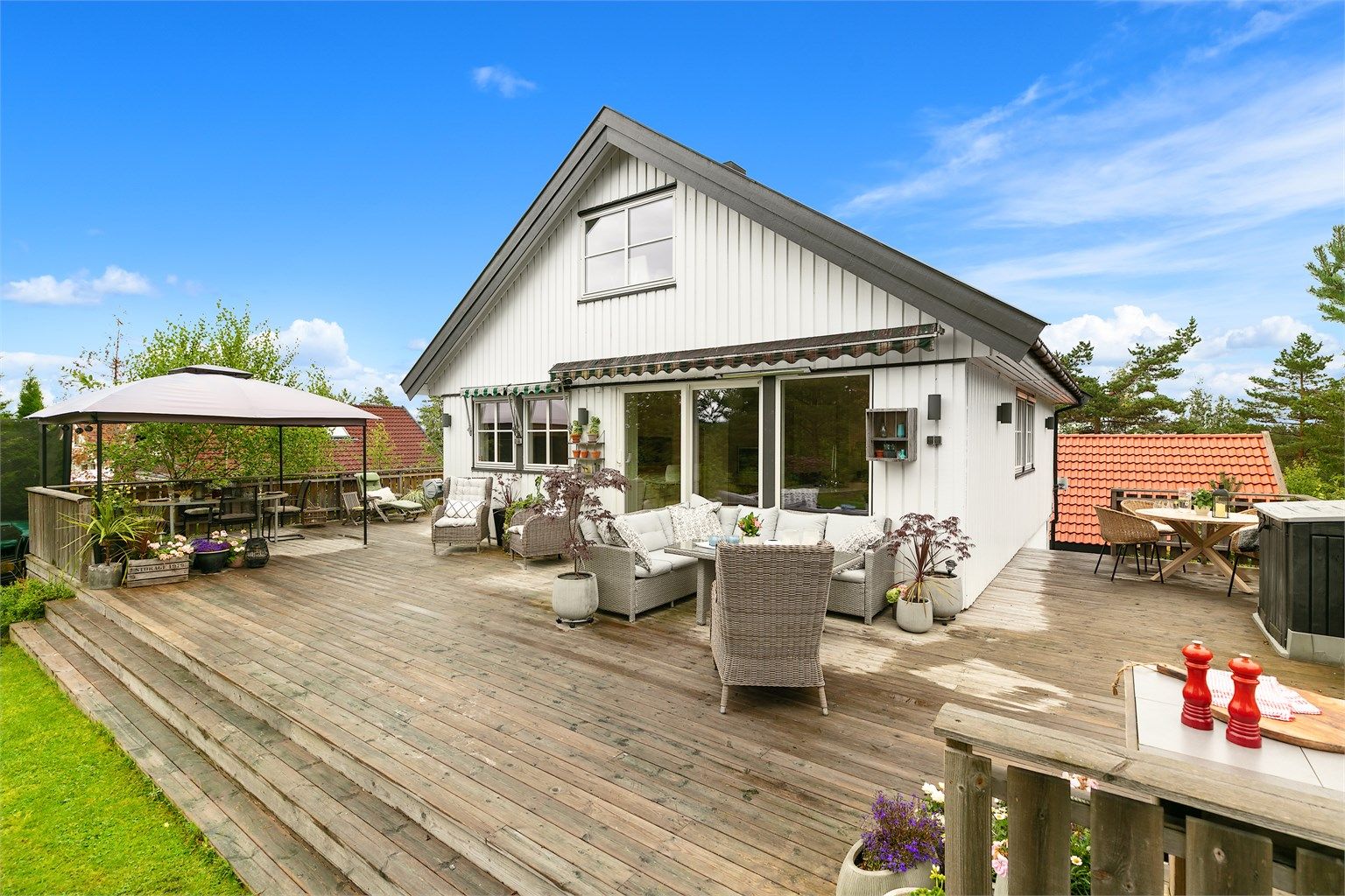 Den romslige terrassen strekker seg langs hele husets bakside og innbyr til både rolige stunder og sosiale sammenkomster.