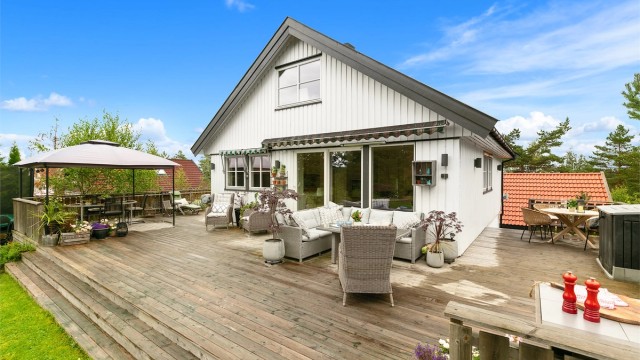 Den romslige terrassen strekker seg langs hele husets bakside og innbyr til både rolige stunder og sosiale sammenkomster.