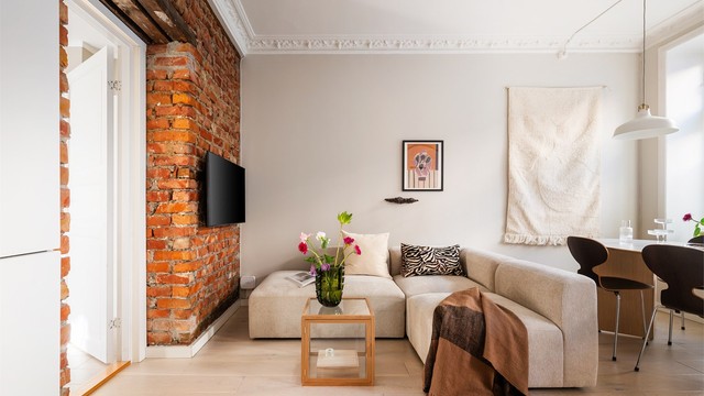 En eksponert teglsteinsvegg gir stuen en rustikk og stilig kontrast til de ellers moderne overflatene.
