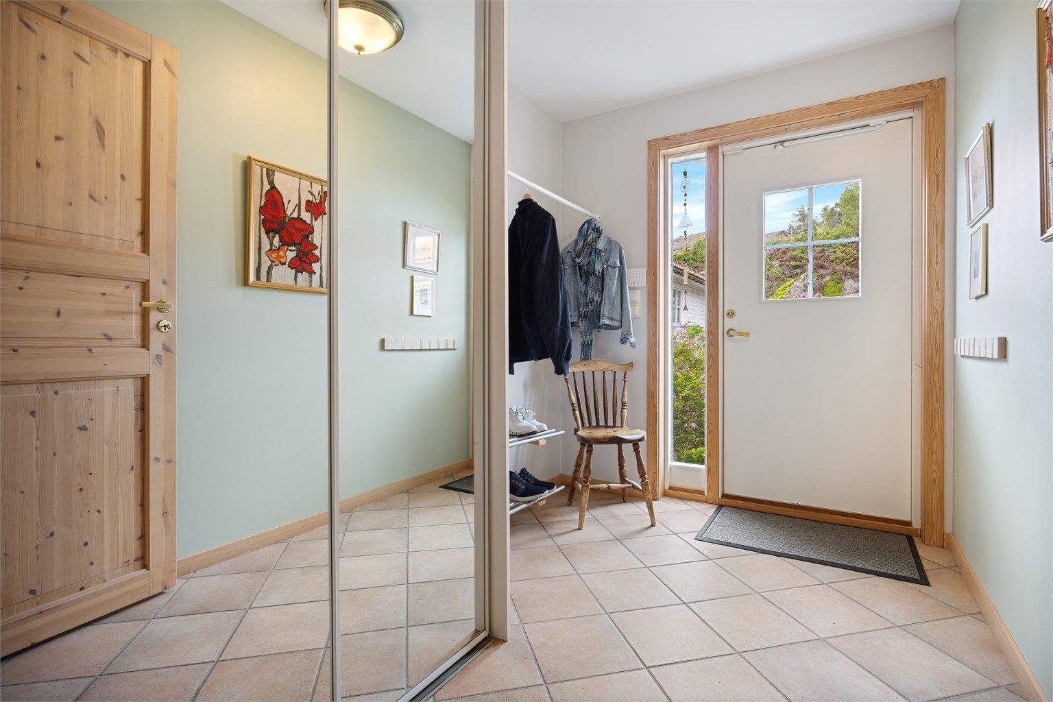 Innbydende og lys entré med stor skyvedørsgarderobe og gode løsninger for oppbevaring av yttertøy.