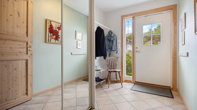 Innbydende og lys entré med stor skyvedørsgarderobe og gode løsninger for oppbevaring av yttertøy.